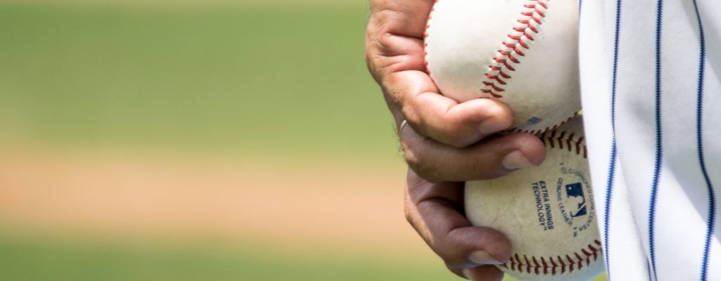 A baseball player holds two balls pausing a moment to visualize his pitch